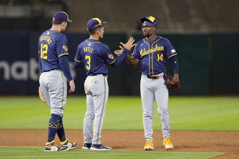 Aug 23, 2024; Oakland, California, USA; Milwaukee Brewers second baseman Andruw Monasterio (14) celebrates with third baseman Joey Ortiz (3) and first baseman Rhys Hoskins (12) after defeating the Oakland Athletics at Oakland-Alameda County Coliseum. Mandatory Credit: Darren Yamashita-USA TODAY Sports