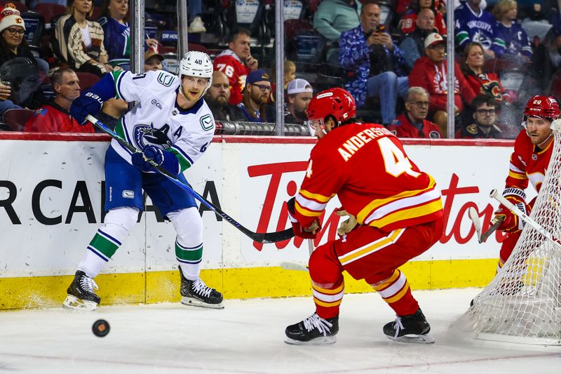 Oct 1, 2025; Calgary, Alberta, CAN; Vancouver Canucks center Elias Pettersson (40) passes the puck against Calgary Flames defenseman Rasmus Andersson (4) during the first period at Scotiabank Saddledome. Mandatory Credit: Sergei Belski-Imagn Images