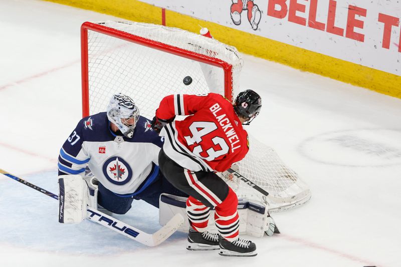 Feb 23, 2024; Chicago, Illinois, USA; Chicago Blackhawks center Colin Blackwell (43) shoots and scores against Winnipeg Jets goaltender Connor Hellebuyck (37) during the second period at United Center. Mandatory Credit: Kamil Krzaczynski-USA TODAY Sports