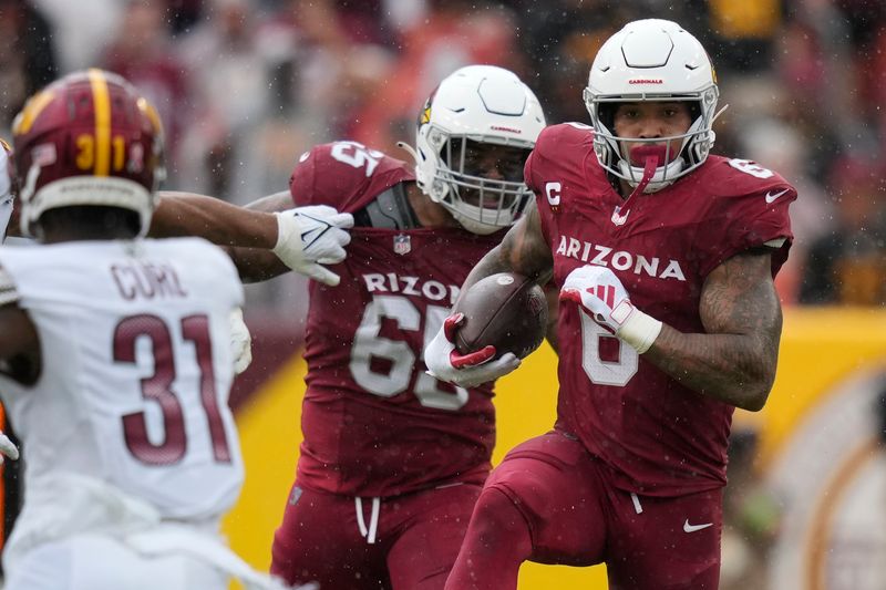 Arizona Cardinals running back James Conner (6) runs with the ball as Washington Commanders safety Kamren Curl (31) and Arizona Cardinals offensive tackle Elijah Wilkinson (65) move in during the second half of an NFL preseason football game, Sunday, Sept. 10, 2023, in Landover, Md. (AP Photo/Alex Brandon)