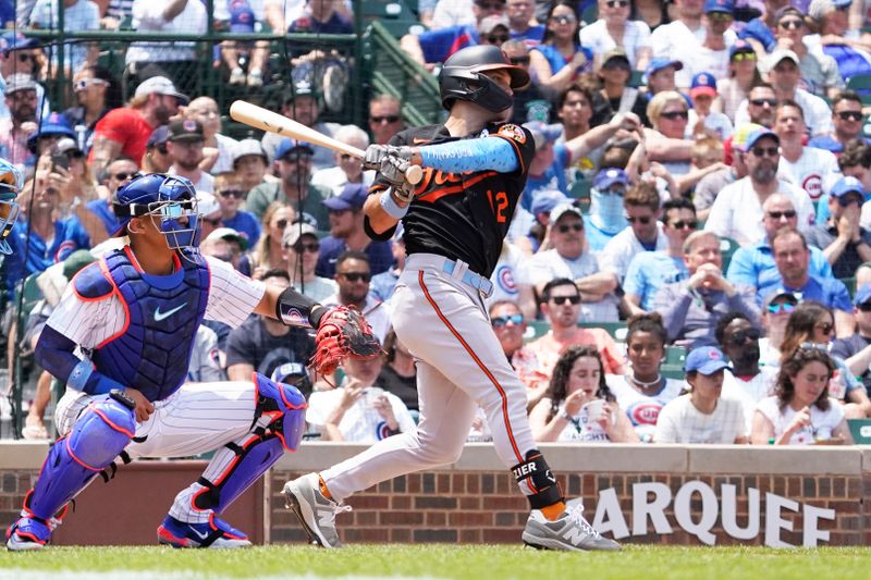 Jun 18, 2023; Chicago, Illinois, USA; Baltimore Orioles second baseman Adam Frazier (12) hits an RBI single against the Chicago Cubs during the sixth inning at Wrigley Field. Mandatory Credit: David Banks-USA TODAY Sports