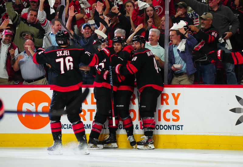 Apr 30, 2024; Raleigh, North Carolina, USA; Carolina Hurricanes center Jack Drury (18) is congratulated by left wing Jordan Martinook (48) and defenseman Tony DeAngelo (77) after his goal against the New York Islanders during the third period in game five of the first round of the 2024 Stanley Cup Playoffs at PNC Arena. Mandatory Credit: James Guillory-USA TODAY Sports