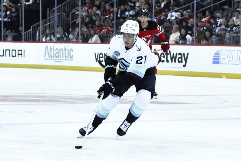 Feb 12, 2024; Newark, New Jersey, USA; Seattle Kraken center Alex Wennberg (21) skates with the puck as New Jersey Devils right wing Nathan Bastian (14) trails during the first period at Prudential Center. Mandatory Credit: John Jones-USA TODAY Sports