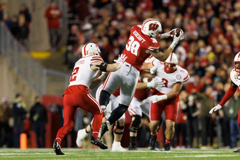 Nov 18, 2023; Madison, Wisconsin, USA;  Wisconsin Badgers tight end Tucker Ashcraft (38) catches a pass in front of Nebraska Cornhuskers defensive back Isaac Gifford (2) during the second quarter at Camp Randall Stadium. Mandatory Credit: Jeff Hanisch-USA TODAY Sports