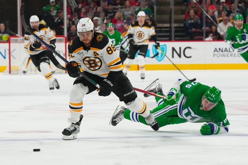 Mar 26, 2023; Raleigh, North Carolina, USA;  Boston Bruins right wing David Pastrnak (88) and Carolina Hurricanes defenseman Brady Skjei (76) chase after the loose puck during the second period at PNC Arena. Mandatory Credit: James Guillory-USA TODAY Sports