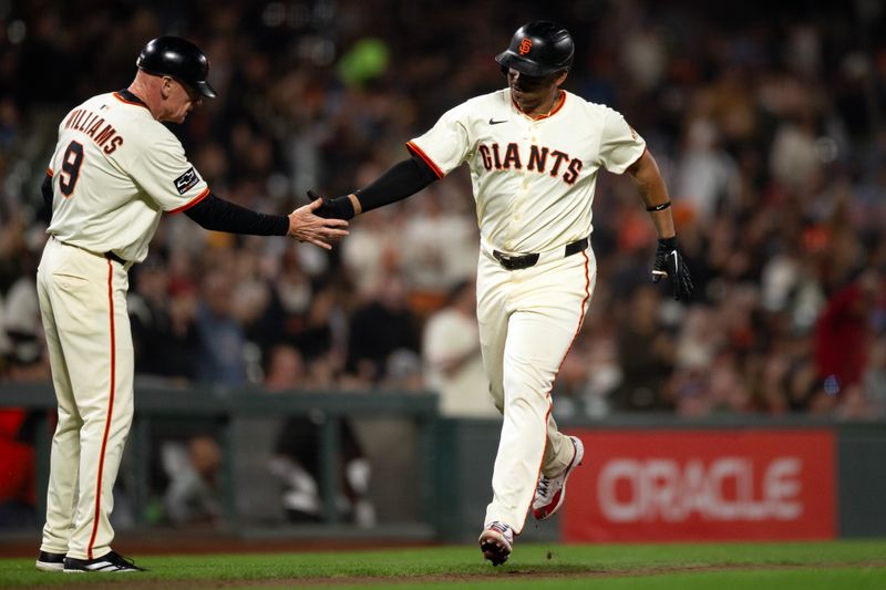 Sep 22, 2025; San Francisco, California, USA; San Francisco Giants first baseman Rafael Devers (16) gets a congratulatory handshake from third base coach Matt Williams (9) as he runs out his solo home run against the St. Louis Cardinals during the fifth inning at Oracle Park. Mandatory Credit: D. Ross Cameron-Imagn Images