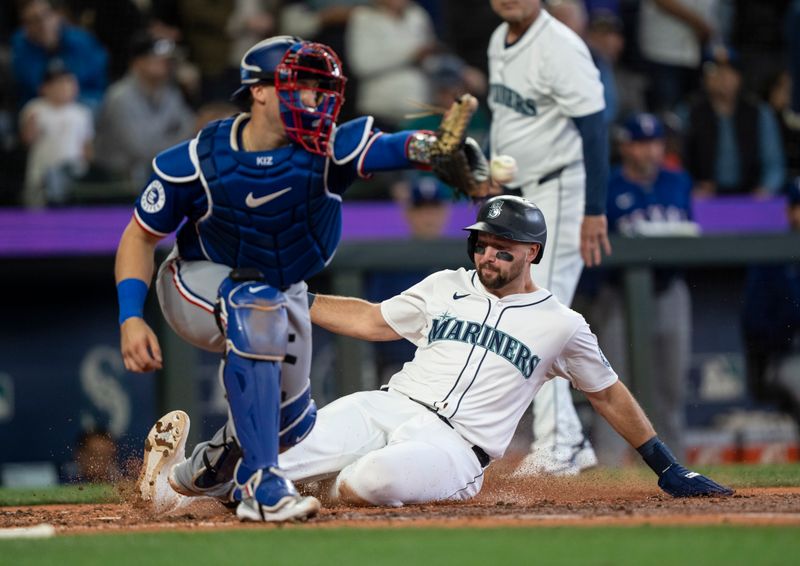 Jun 15, 2024; Seattle, Washington, USA; Seattle Mariners designated hitter Cal Raleigh (29) slides safely into home plate to score a run before Texas Rangers catcher Andrew Knizner (12) can make a tag during the third inning at T-Mobile Park. Mandatory Credit: Stephen Brashear-USA TODAY Sports