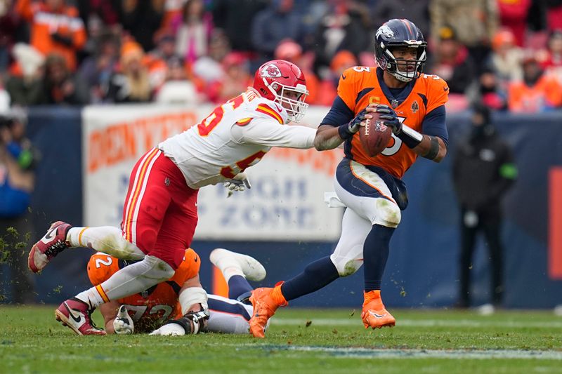 Denver Broncos quarterback Russell Wilson (3) scrambles as he is hit by Kansas City Chiefs defensive end George Karlaftis during the first half of an NFL football game Sunday, Oct. 29, 2023, in Denver. The hit by Karlaftis caused Wilson to fumble and was recovered by the Chiefs' Willie Gay. (AP Photo/Jack Dempsey)