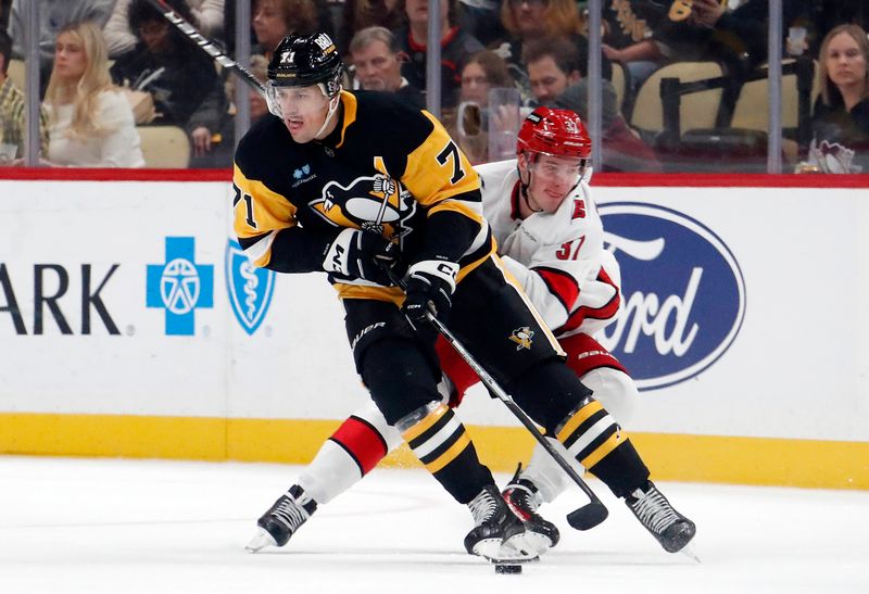 Oct 18, 2024; Pittsburgh, Pennsylvania, USA;  Pittsburgh Penguins center Evgeni Malkin (71) moves the puck against Carolina Hurricanes right wing Andrei Svechnikov (37) during the second period at PPG Paints Arena. Mandatory Credit: Charles LeClaire-Imagn Images