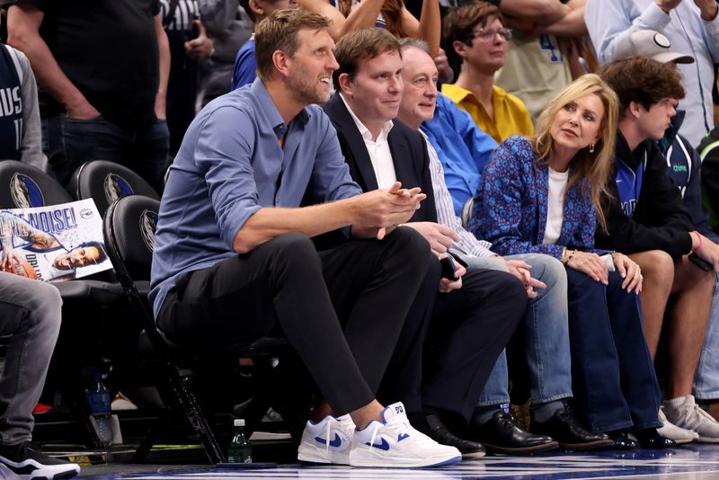 DALLAS, TEXAS - MARCH 13: Dirk Nowitzki (L) smiles while sitting next to Dallas Mavericks governor Patrick Dumont (R) in the first half against the Golden State Warriors at American Airlines Center on March 13, 2024 in Dallas, Texas. NOTE TO USER: User expressly acknowledges and agrees that, by downloading and or using this photograph, User is consenting to the terms and conditions of the Getty Images License Agreement. (Photo by Tim Heitman/Getty Images)