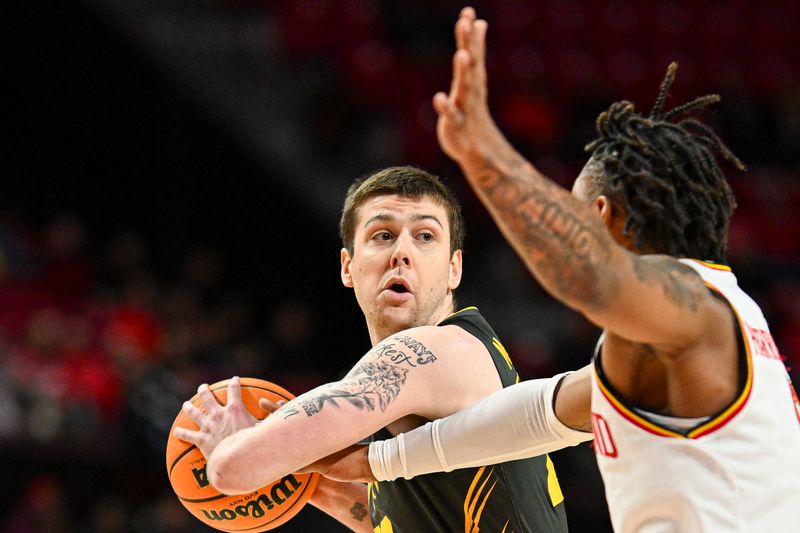 Feb 14, 2024; College Park, Maryland, USA;  Iowa Hawkeyes forward Patrick McCaffery (22) looks to pass and Maryland Terrapins guard DeShawn Harris-Smith (5) defends at Xfinity Center. Mandatory Credit: Tommy Gilligan-USA TODAY Sports