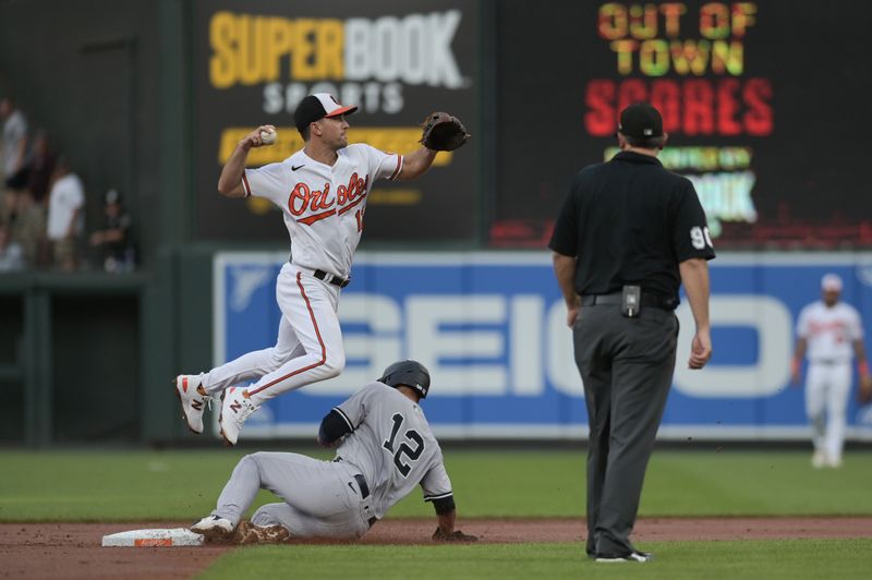 Jul 29, 2023; Baltimore, Maryland, USA;  Baltimore Orioles second baseman Adam Frazier (12) leaps as New York Yankees center fielder Isiah Kiner-Falefa (12) slides into second base during the second inning at Oriole Park at Camden Yards. Mandatory Credit: Tommy Gilligan-USA TODAY Sports