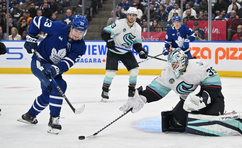 Oct 31, 2024; Toronto, Ontario, CAN;  Seattle Kraken goalie Joey Daccord (35) clears the puck away from Toronto Maple Leafs forward Matthews Knies in the first period at Scotiabank Arena. Mandatory Credit: Dan Hamilton-Imagn Images