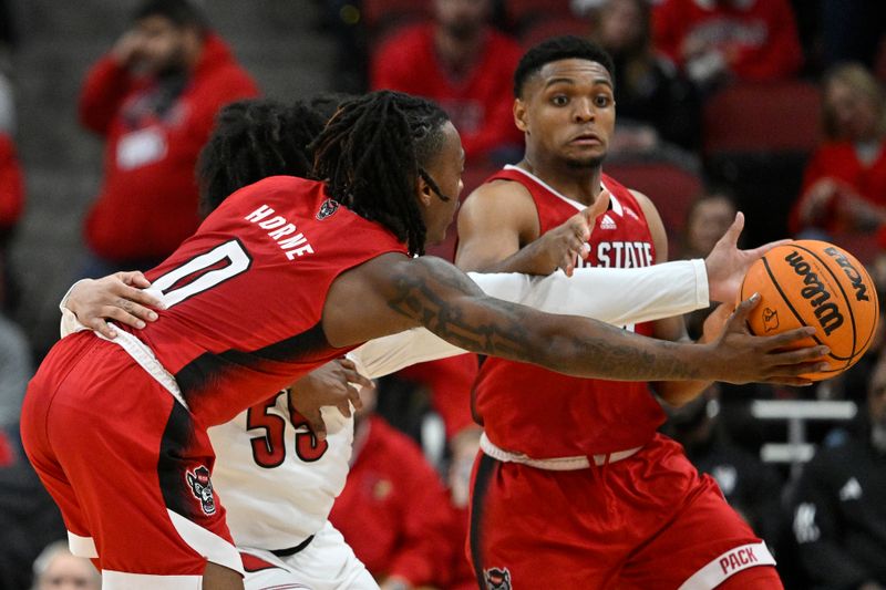 Jan 13, 2024; Louisville, Kentucky, USA;  North Carolina State Wolfpack guard DJ Horne (0) tries to hand the ball off to guard Casey Morsell (14) against Louisville Cardinals guard Skyy Clark (55) during the second half at KFC Yum! Center.  Mandatory Credit: Jamie Rhodes-USA TODAY Sports