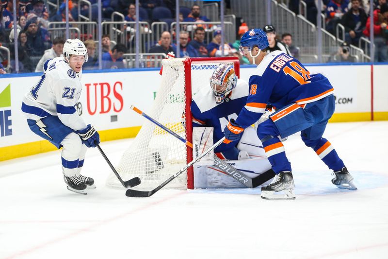 Feb 24, 2024; Elmont, New York, USA;  Tampa Bay Lightning center Brayden Point (21) and New York Islanders left wing Pierre Engvall (18) battle for control of the puck in the first period at UBS Arena. Mandatory Credit: Wendell Cruz-USA TODAY Sports