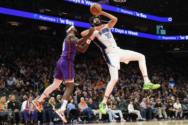 PHOENIX, ARIZONA - NOVEMBER 18: Goga Bitadze #35 of the Orlando Magic is fouled by Royce O'Neale #00 of the Phoenix Suns as he attempts a shot during the first half of the NBA game at Footprint Center on November 18, 2024 in Phoenix, Arizona.  NOTE TO USER: User expressly acknowledges and agrees that, by downloading and/or using this photograph, user is consenting to the terms and conditions of the Getty Images License Agreement. (Photo by Christian Petersen/Getty Images)