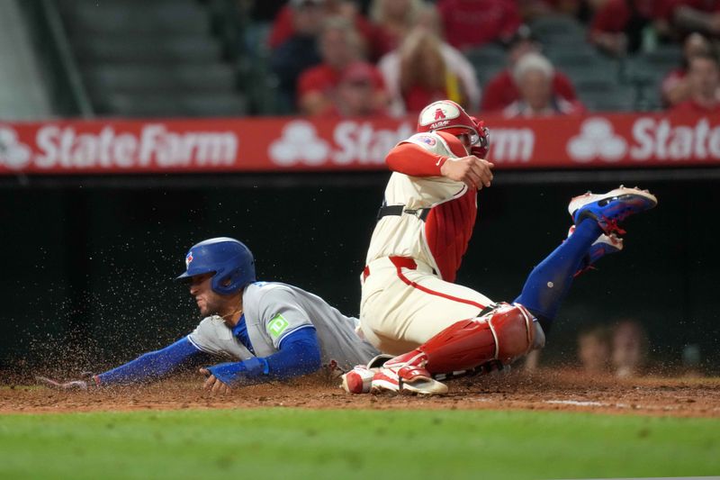 May 8, 2025; Anaheim, California, USA; Toronto Blue Jays designated hitter George Springer (4) slides into home plate to beat a throw to Los Angeles Angels catcher Logan O'Hoppe (14) to score on a throwing error in the sixth inning at Angel Stadium. Mandatory Credit: Kirby Lee-Imagn Images