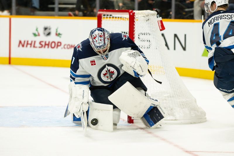 Nov 23, 2024; Nashville, Tennessee, USA;  Winnipeg Jets goaltender Eric Comrie (1) blocks the puck against the Nashville Predators during the third period at Bridgestone Arena. Mandatory Credit: Steve Roberts-Imagn Images