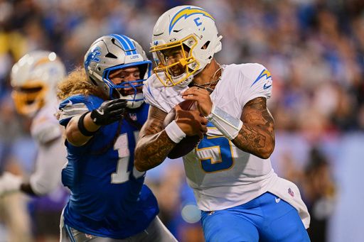 Detroit Lions linebacker Grant Stuard, left, pursues Los Angeles Chargers quarterback Trey Lance (5) in the first half of the Pro Football Hall of Fame NFL preseason game Thursday, July 31, 2025, in Canton, Ohio. (AP Photo/David Dermer)