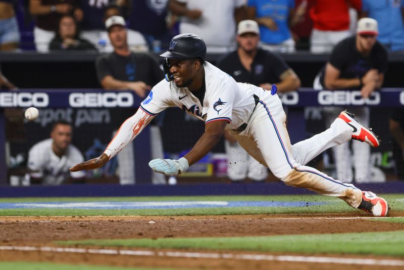 Jul 4, 2024; Miami, Florida, USA; Miami Marlins right fielder Jesus Sanchez (12) slides at home plate but cannot score against a throw by Boston Red Sox left fielder Jarren Duran (not pictured) during the ninth inning at loanDepot Park. Mandatory Credit: Sam Navarro-USA TODAY Sports