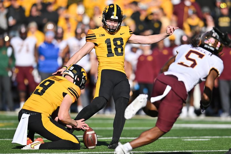 Oct 21, 2023; Iowa City, Iowa, USA; Iowa Hawkeyes place kicker Drew Stevens (18) kicks an extra point as punter Tory Taylor (9) holds as Minnesota Golden Gophers defensive back Justin Walley (5) goes for the block during the second quarter at Kinnick Stadium. Mandatory Credit: Jeffrey Becker-USA TODAY Sports