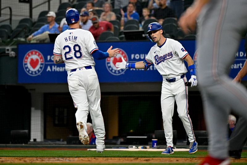 May 2, 2024; Arlington, Texas, USA; Texas Rangers catcher Jonah Heim (28) and center fielder Evan Carter (32) celebrates after Heim scores against the Washington Nationals during the second inning at Globe Life Field. Mandatory Credit: Jerome Miron-USA TODAY Sports