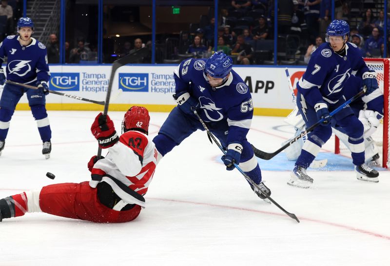 Sep 26, 2025; Tampa, Florida, USA; Tampa Bay Lightning left wing Dylan Duke (53) skates with the puck as Carolina Hurricanes right wing Givani Smith (42) defends during the second period at Benchmark International Arena. Mandatory Credit: Kim Klement Neitzel-Imagn Images