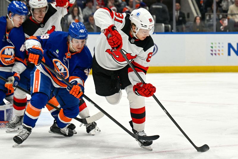 Dec 23, 2025; Elmont, New York, USA;  New Jersey Devils right wing Arseny Gritsyuk (81) passes the puck while being defended by New York Islanders right wing Max Shabanov (49) during the third period at UBS Arena. Mandatory Credit: Dennis Schneidler-Imagn Images