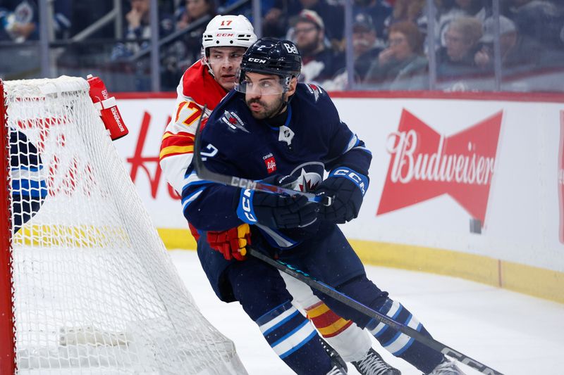 Jan 26, 2025; Winnipeg, Manitoba, CAN;  Calgary Flames forward Yegor Sharangovich (17) and Winnipeg Jets defenseman Dylan DeMelo (2) skate after the puck during the first period at Canada Life Centre. Mandatory Credit: Terrence Lee-Imagn Images