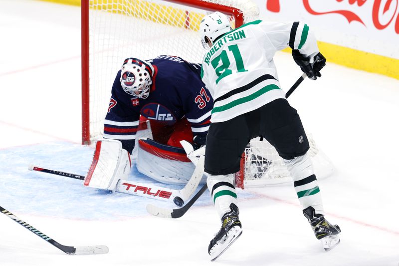 Nov 9, 2024; Winnipeg, Manitoba, CAN; Winnipeg Jets goaltender Connor Hellebuyck (37) makes a stick save on a Dallas Stars left wing Jason Robertson (21) shot in the third period at Canada Life Centre. Mandatory Credit: James Carey Lauder-Imagn Images