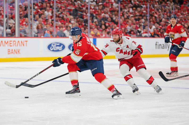 May 26, 2025; Sunrise, Florida, USA; Florida Panthers center Anton Lundell (15) and Carolina Hurricanes defenseman Jaccob Slavin (74) race for the puck during the second period in game four of the Eastern Conference Final of the 2025 Stanley Cup Playoffs at Amerant Bank Arena. Mandatory Credit: Sam Navarro-Imagn Images