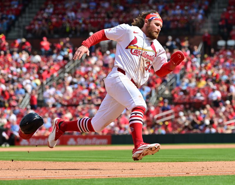 Apr 13, 2025; St. Louis, Missouri, USA; St. Louis Cardinals infield Brendan Donovan (33) loses his batting helmet as he heads to third base off a double by St. Louis Cardinals third baseman Nolan Arenado (28, not shown) at Busch Stadium. Mandatory Credit: Tim Vizer-Imagn Images