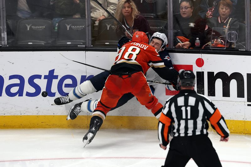 Nov 9, 2025; Anaheim, California, USA;  Anaheim Ducks defenseman Pavel Mintyukov (98) checks Winnipeg Jets center Parker Ford (25) into the boards during the third period at Honda Center. Mandatory Credit: Kiyoshi Mio-Imagn Images