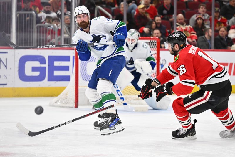 Feb 13, 2024; Chicago, Illinois, USA; Vancouver Canucks defenseman Filip Hronek (17) passes the puck past Chicago Blackhawks forward Jason Dickinson (16) in the third period at United Center. Mandatory Credit: Jamie Sabau-USA TODAY Sports