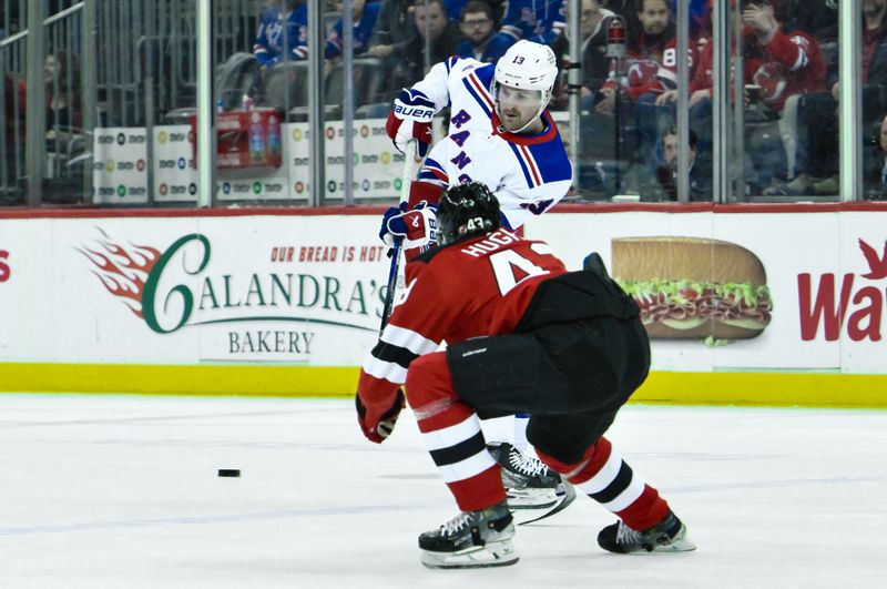 Feb 22, 2024; Newark, New Jersey, USA; New York Rangers left wing Alexis Lafreniere (13) passes the puck while being defended by New Jersey Devils defenseman Luke Hughes (43) during the first period at Prudential Center. Mandatory Credit: John Jones-USA TODAY Sports