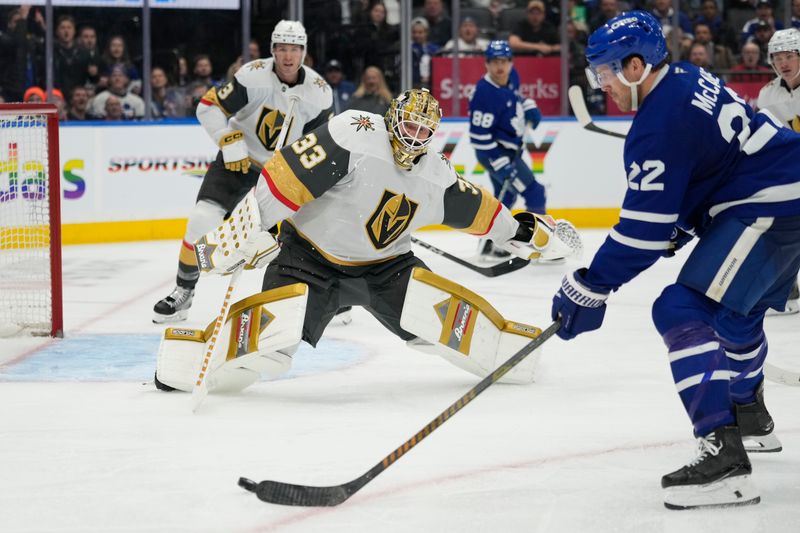 Nov 20, 2024; Toronto, Ontario, CAN; Vegas Golden Knights goaltender Adin Hill (33) defends the goal against Toronto Maple Leafs defenceman Jake McCabe (22) during the third period at Scotiabank Arena. Mandatory Credit: John E. Sokolowski-Imagn Images