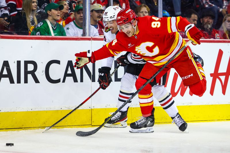 Oct 15, 2024; Calgary, Alberta, CAN; Calgary Flames defenseman Brayden Pachal (94) and Chicago Blackhawks right wing Joey Anderson (22) battles for the puck during the first period at Scotiabank Saddledome. Mandatory Credit: Sergei Belski-Imagn Images