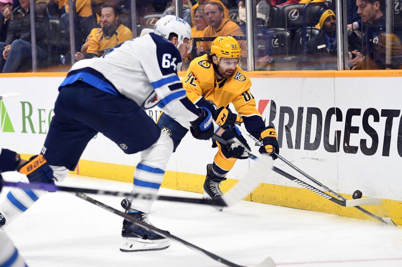 Apr 9, 2024; Nashville, Tennessee, USA; Nashville Predators center Tommy Novak (82) handles the puck behind the net against Winnipeg Jets defenseman Logan Stanley (64) during the first period at Bridgestone Arena. Mandatory Credit: Christopher Hanewinckel-USA TODAY Sports