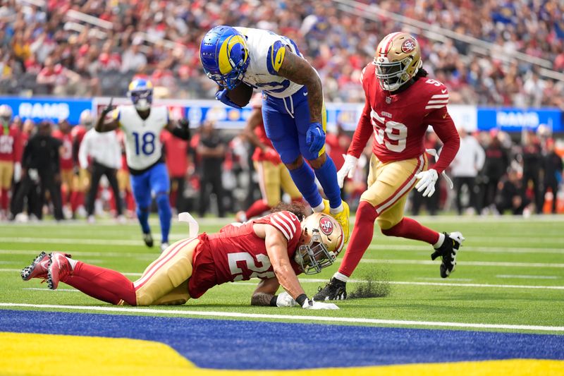 Los Angeles Rams running back Kyren Williams, top, flips into the end zone to score against San Francisco 49ers safety Talanoa Hufanga, bottom, and linebacker De'Vondre Campbell during the first half of an NFL football game, Sunday, Sept. 22, 2024, in Inglewood, Calif. (AP Photo/Ashley Landis)