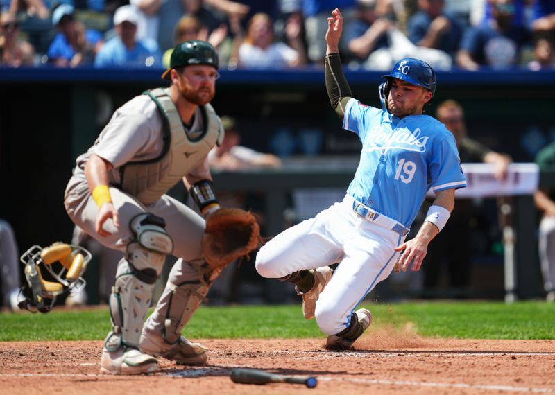 May 19, 2024; Kansas City, Missouri, USA; Kansas City Royals second baseman Michael Massey (19) slides into home to score a run against Oakland Athletics catcher Kyle McCann (52) during the sixth inning at Kauffman Stadium. Mandatory Credit: Jay Biggerstaff-USA TODAY Sports