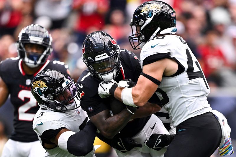 Jacksonville Jaguars defensive end Travon Walker (44) and safety Andre Cisco (5) tackle Houston Texans wide receiver Stefon Diggs (1) in the second quarter during an NFL football game, Sunday, Sept. 29, 2024 in Houston. (AP Photo/Maria Lysaker)