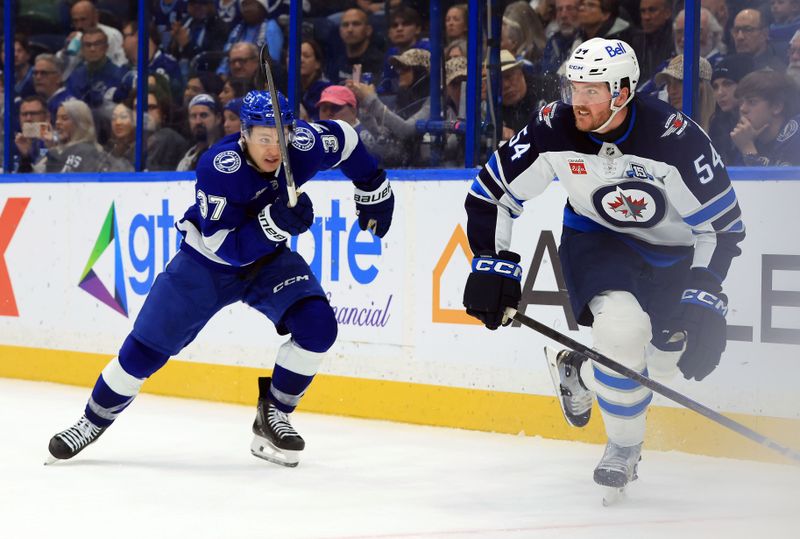 Jan 29, 2026; Tampa, Florida, USA; Tampa Bay Lightning center Yanni Gourde (37) and Winnipeg Jets defenseman Dylan Samberg (54) skate after the puck during the third period at Benchmark International Arena. Mandatory Credit: Kim Klement Neitzel-Imagn Images