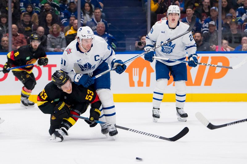 Jan 20, 2024; Vancouver, British Columbia, CAN; Toronto Maple Leafs forward John Tavares (91) checks Vancouver Canucks forward Teddy Blueger (53) into the ice in the first period at Rogers Arena. Mandatory Credit: Bob Frid-USA TODAY Sports