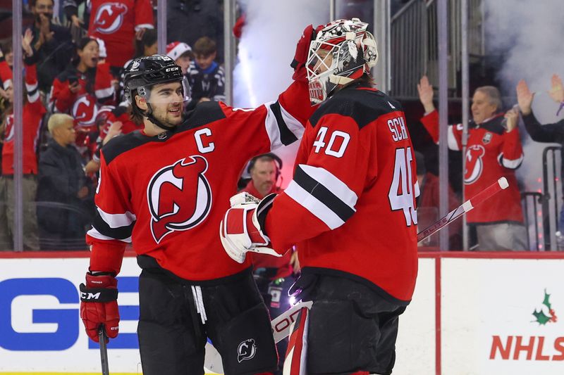 Nov 28, 2023; Newark, New Jersey, USA; New Jersey Devils center Nico Hischier (13) and goaltender Akira Schmid (40) celebrate their win over the New York Islanders at Prudential Center. Mandatory Credit: Ed Mulholland-USA TODAY Sports