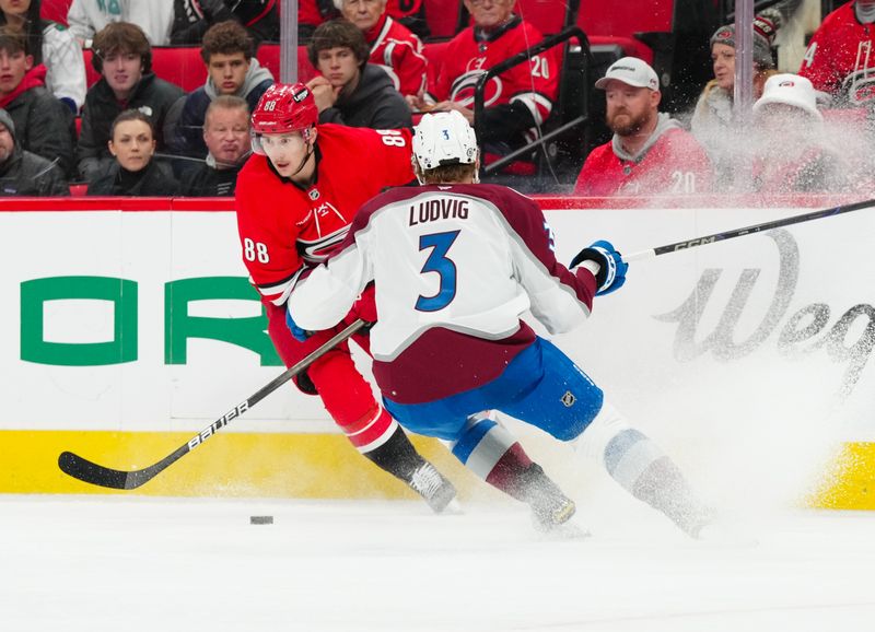 Dec 5, 2024; Raleigh, North Carolina, USA;  Carolina Hurricanes center Martin Necas (88) holds onto the puck against Colorado Avalanche defenseman John Ludvig (3) during the first period at Lenovo Center. Mandatory Credit: James Guillory-Imagn Images