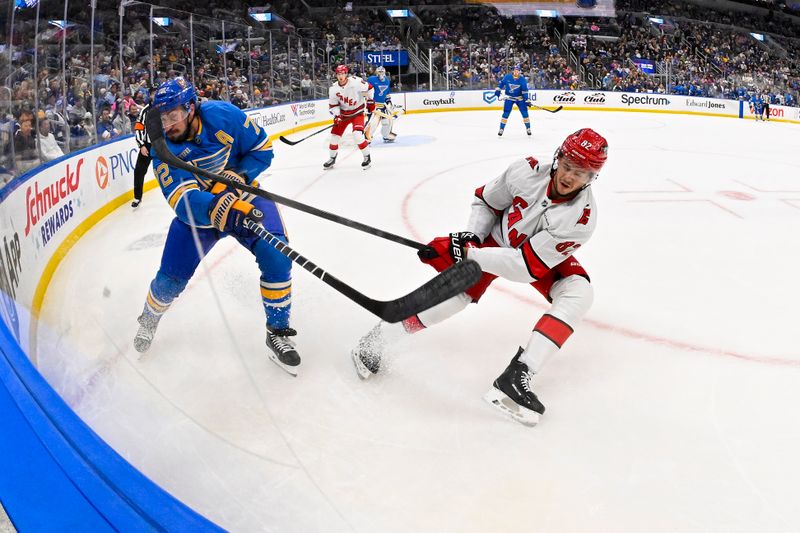 Oct 19, 2024; St. Louis, Missouri, USA;  St. Louis Blues defenseman Justin Faulk (72) clears the puck past Carolina Hurricanes center Jesperi Kotkaniemi (82) during the first period at Enterprise Center. Mandatory Credit: Jeff Curry-Imagn Images