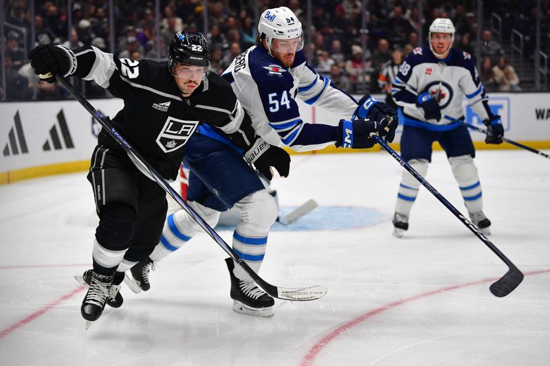 Dec 13, 2023; Los Angeles, California, USA; Los Angeles Kings left wing Kevin Fiala (22) plays for the puck against Winnipeg Jets defenseman Dylan Samberg (54) during the second period at Crypto.com Arena. Mandatory Credit: Gary A. Vasquez-USA TODAY Sports