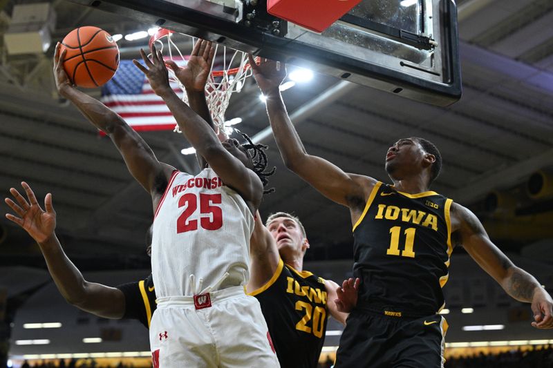 Feb 17, 2024; Iowa City, Iowa, USA; Wisconsin Badgers guard John Blackwell (25) goes to the basket as Iowa Hawkeyes guard Tony Perkins (11) and forward Payton Sandfort (20) defend during the first half at Carver-Hawkeye Arena. Mandatory Credit: Jeffrey Becker-USA TODAY Sports