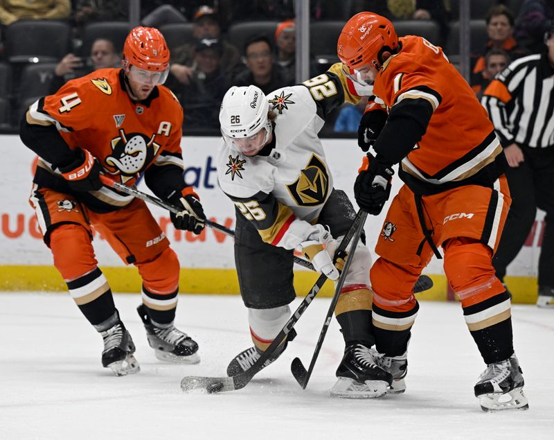 Dec 4, 2024; Anaheim, California, USA; Vegas Golden Knights right wing Alexander Holtz (26) controls the puck against Anaheim Ducks defenseman Radko Gudas (7) and defenseman Cam Fowler (4) during the first period at Honda Center. Mandatory Credit: Alex Gallardo-Imagn Images