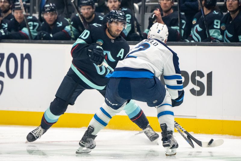 Oct 24, 2024; Seattle, Washington, USA;  Seattle Kraken forward Matty Beniers (10) skates against Winnipeg Jets defenseman Dylan DeMelo (2) during the first period at Climate Pledge Arena. Mandatory Credit: Stephen Brashear-Imagn Images